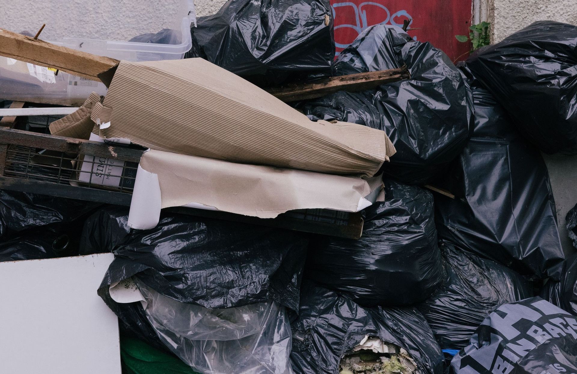 A pile of garbage in front of a graffiti-covered red door with urban decay elements.