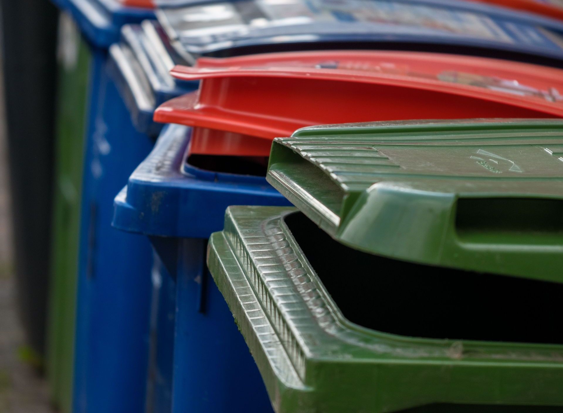 Row of colorful waste bins against a brick wall in Almere, Netherlands.