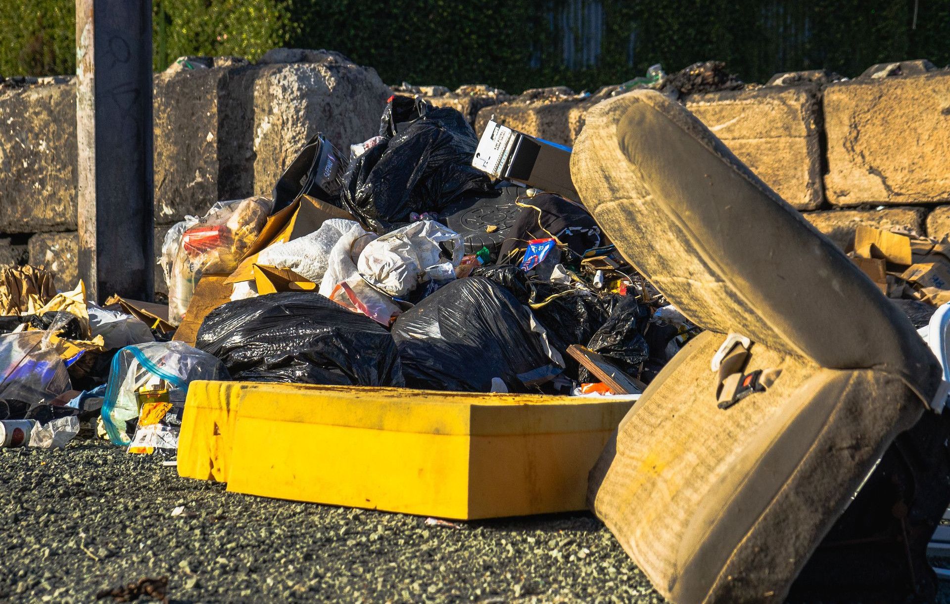 Outdoor scene of a garbage pile including a discarded mattress and various waste materials.