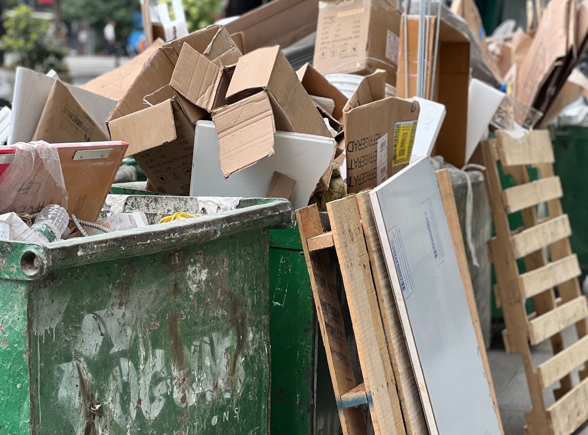 Piled cardboard boxes and waste in a city dumpster highlight urban recycling.
