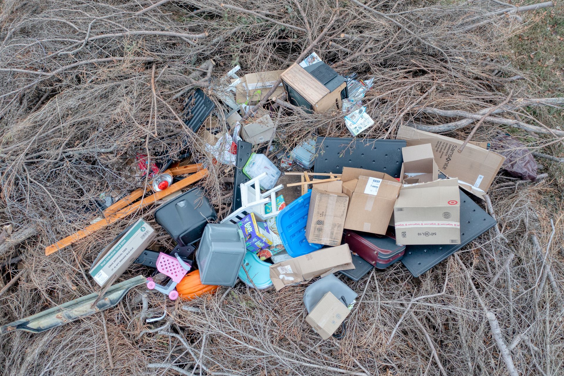 Aerial view of mixed trash and debris scattered in a dry, natural environment.